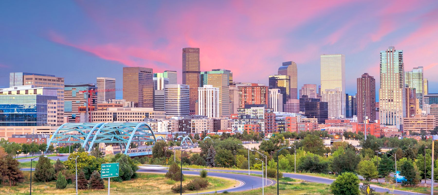 Denver, Colorado skyline at sunset with a vibrant pink and purple sky reflecting off the city’s modern skyscrapers