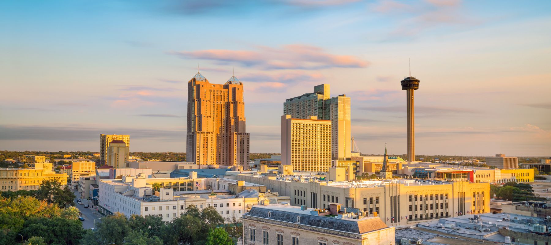 A scenic view of downtown San Antonio, Texas with the Tower of the Americas and surrounding high-rise buildings at sunset